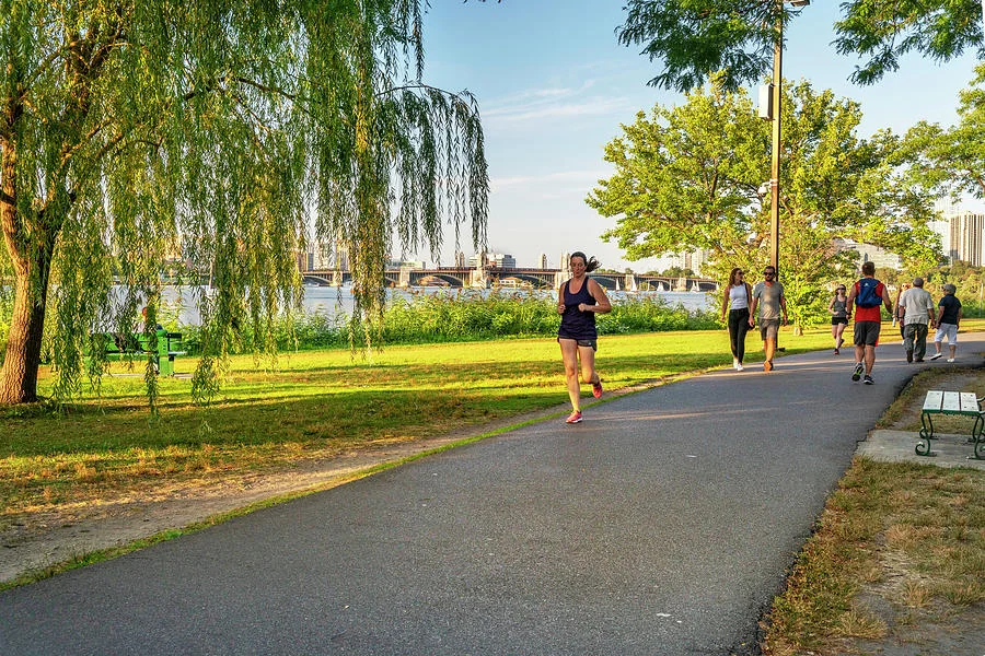 A small group of runners mid long run on a waterfront path under flat overcast sky.