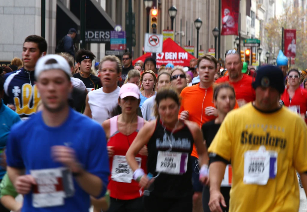 Close crop of a runner's feet mid-stride on painted road markings at goal marathon pace, low camera angle.