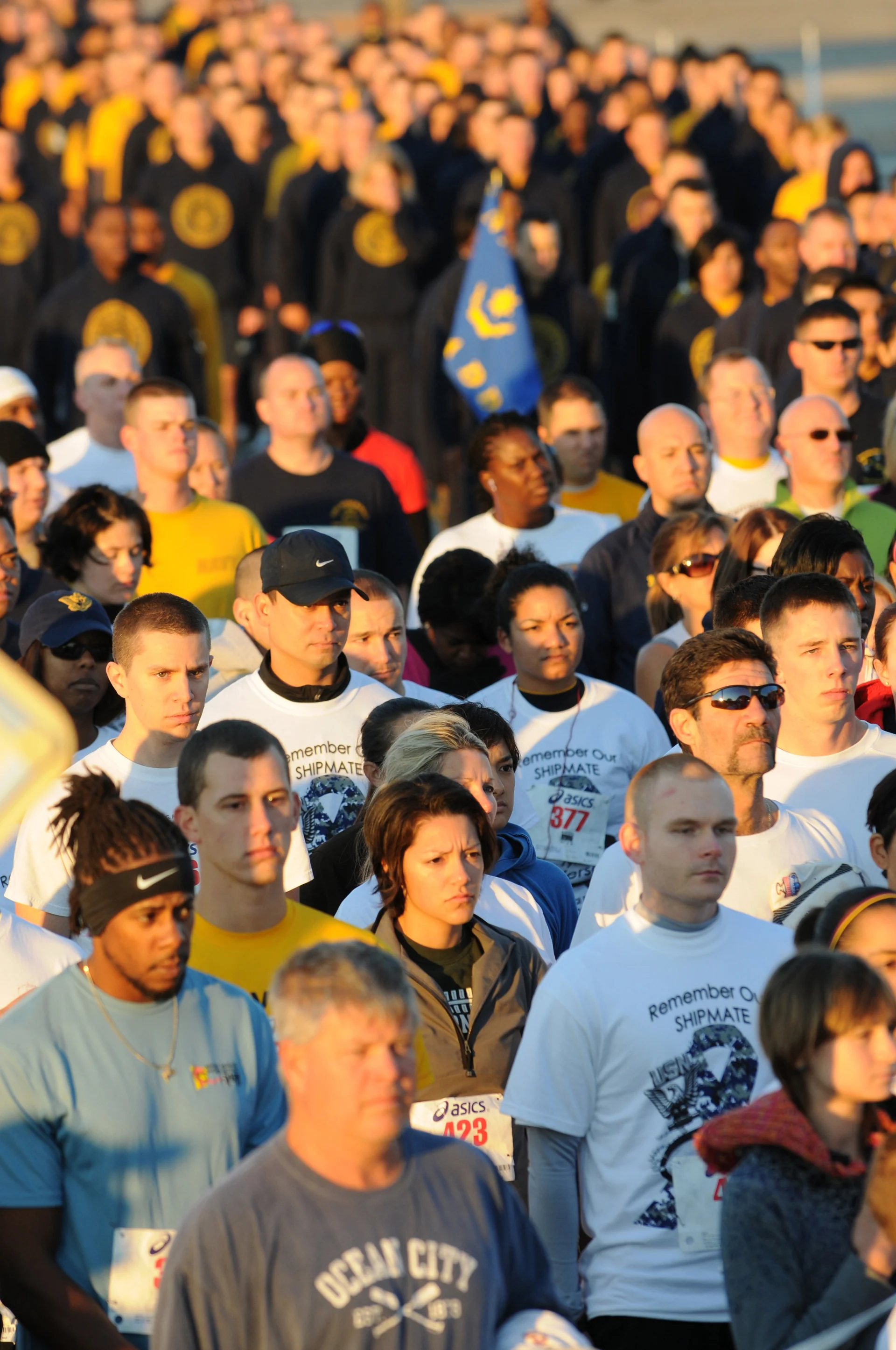 Everyday runners bunched at a weekend 5K start line, seen from behind on an overcast morning.