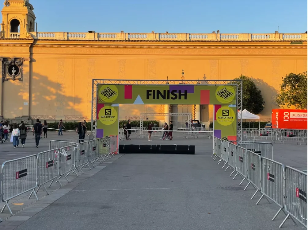 An empty marathon finish-line arch silhouetted against a low sun, finisher tape rippling in the wind.