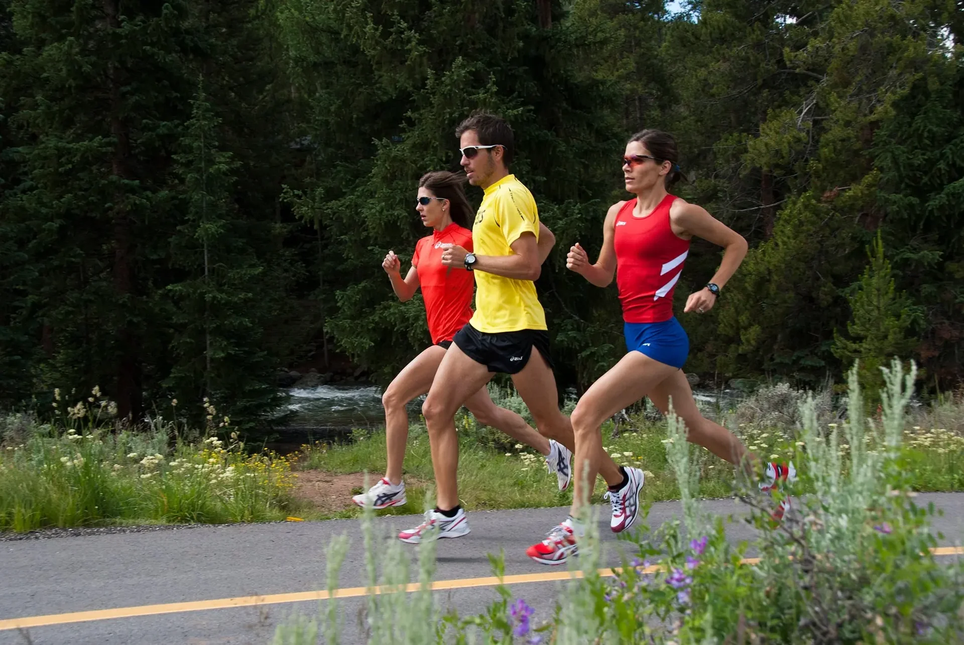 Two runners jogging side by side on a quiet neighborhood road at golden hour, framed from the waist down.