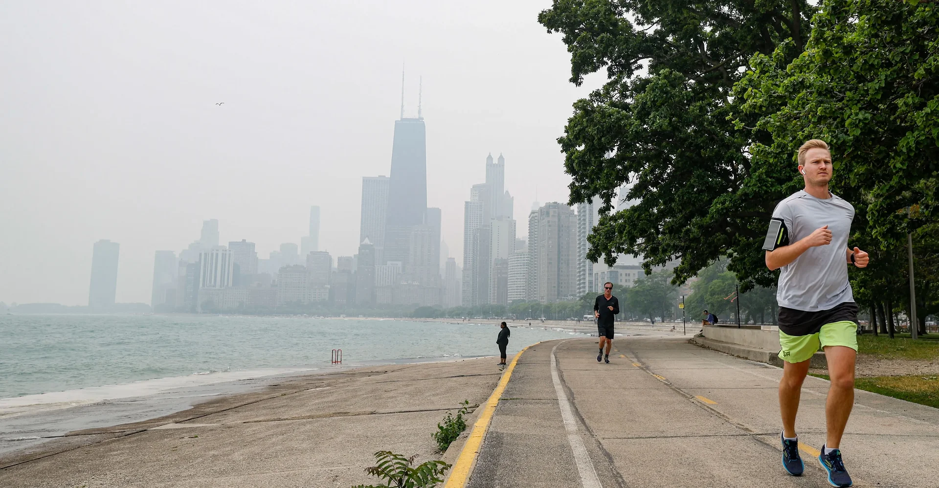 A lone runner on an open road under a hazy amber sky, distant hills blurred by wildfire smoke.