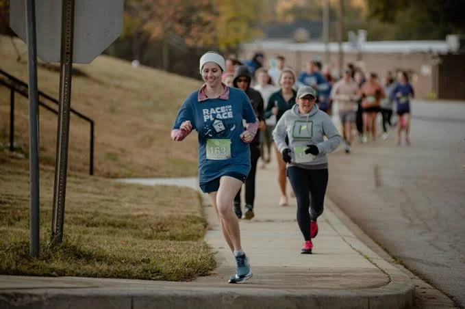 A sports watch on a runner's wrist mid-stride showing a 6:52 mile split and heart rate on a bright display.