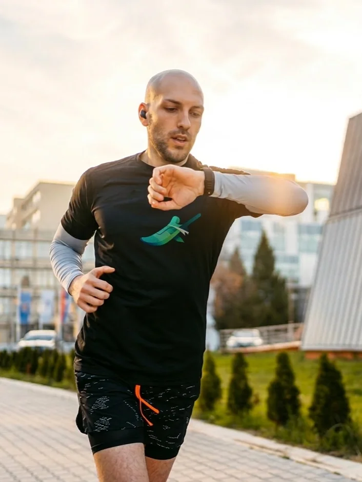 A runner at sunset, thoughtfully reviewing training data on his watch to adjust his future workout intensity