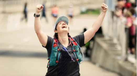 Erin crossing the Mesa Marathon finish line with arms raised