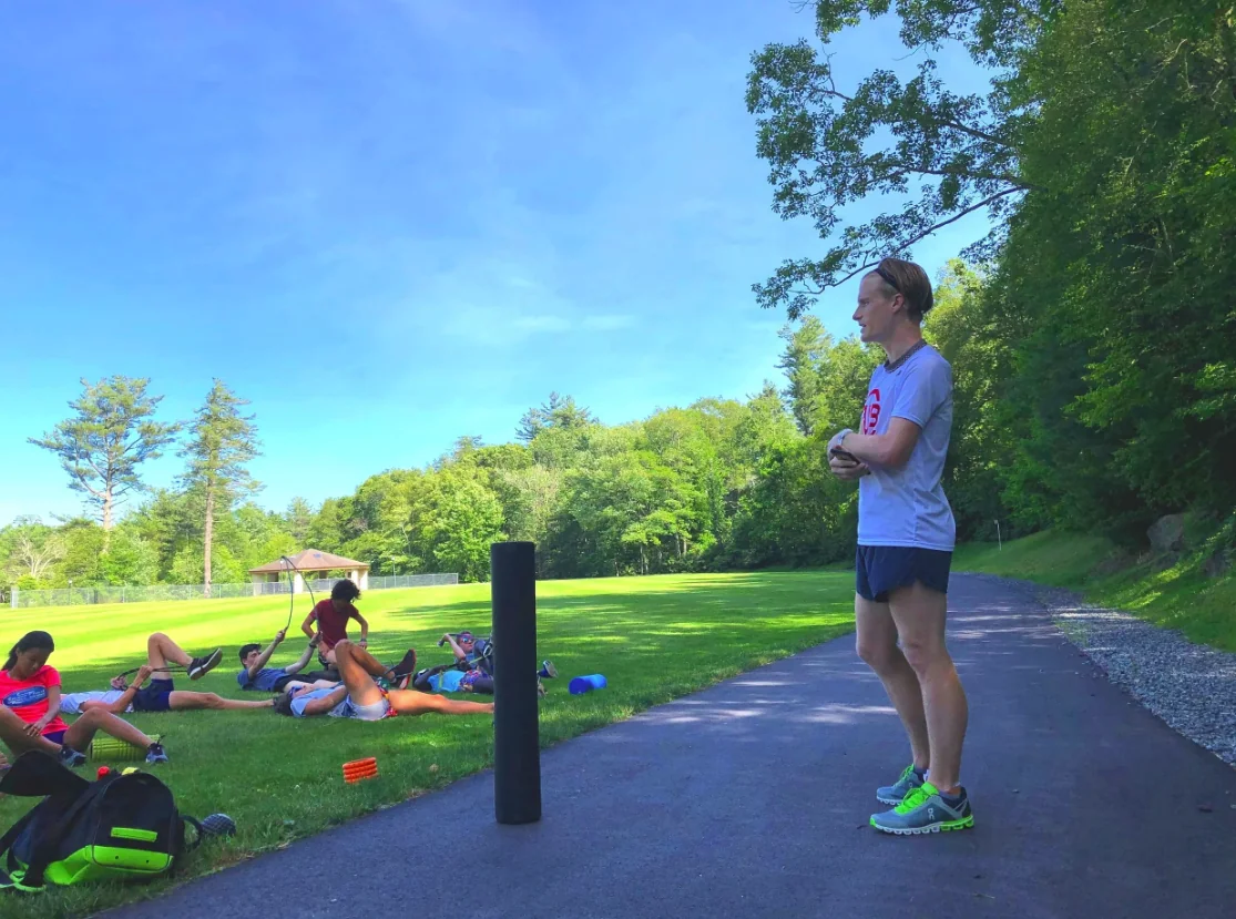 A high-school cross-country coach watching strength work
