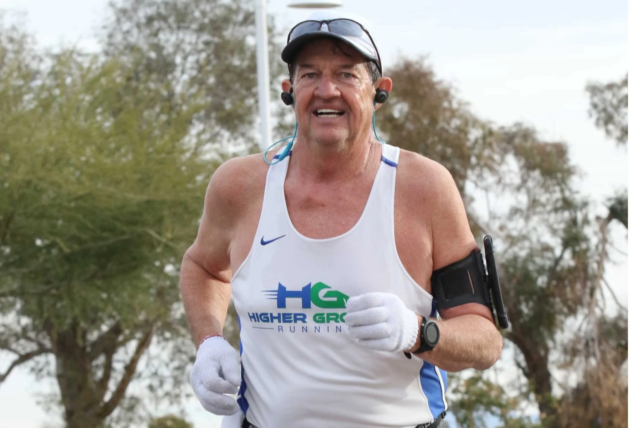 Marvin smiling mid-race in his club singlet, headphones in