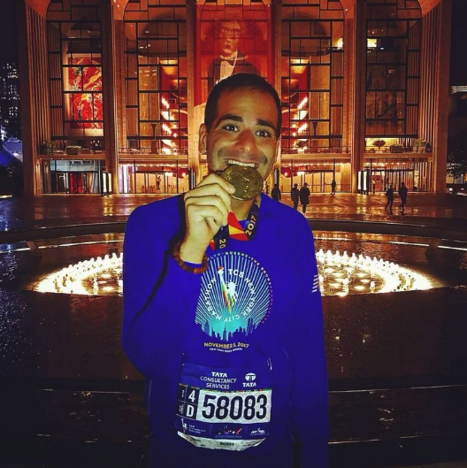 Joel with an NYC Marathon medal at Lincoln Center