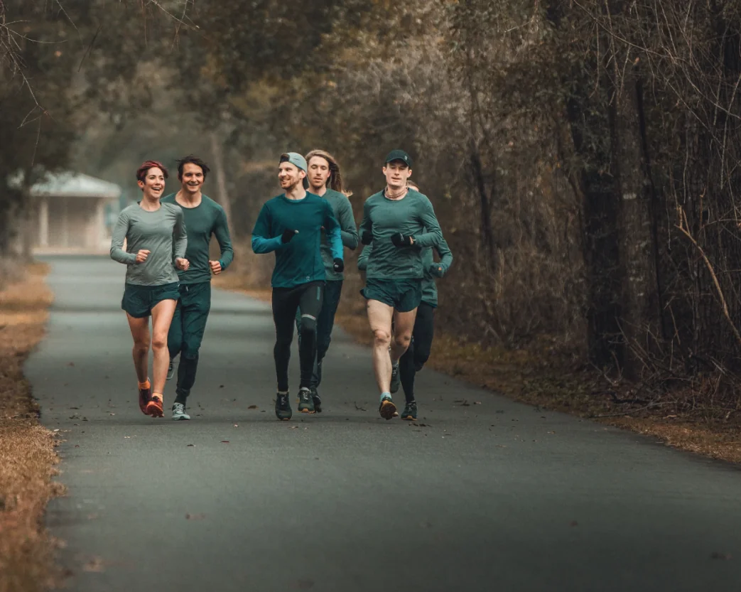 A group of runners training together along a tree-lined trail on a cool morning