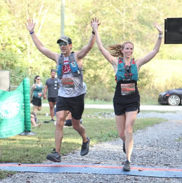 Hal and a teammate crossing a trail marathon finish line with arms raised